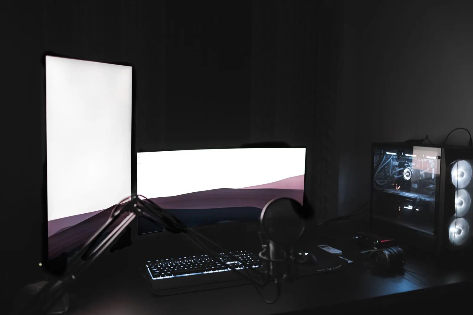 A home streaming setup lit by a ring light with a camera and desk in a dark room